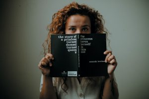 Young woman holding a book which demonstrates reading as a route to independence
